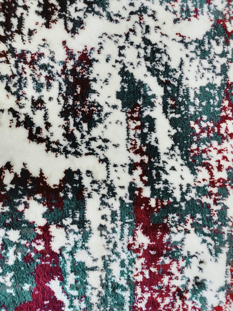 A close-up of the Jingle Frost Rug featuring a modern abstract design with a mix of white, deep red, and dark green colors, with a soft and textured surface.