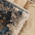 A close-up of the Nebula Script Rug featuring plush abstract patterns in blue, gray, black, and orange. Handmade and available in Mumbai, Thane, India.