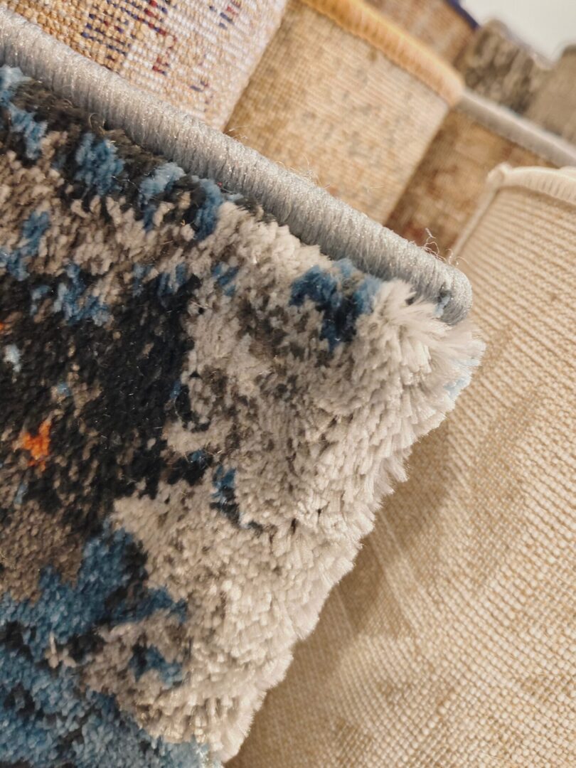 A close-up of the Nebula Script Rug featuring plush abstract patterns in blue, gray, black, and orange. Handmade and available in Mumbai, Thane, India.