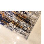 An abstract rug design with vertical streaks in shades of blue, orange, and gray, showcasing a modern and contemporary handtufted wool pattern.