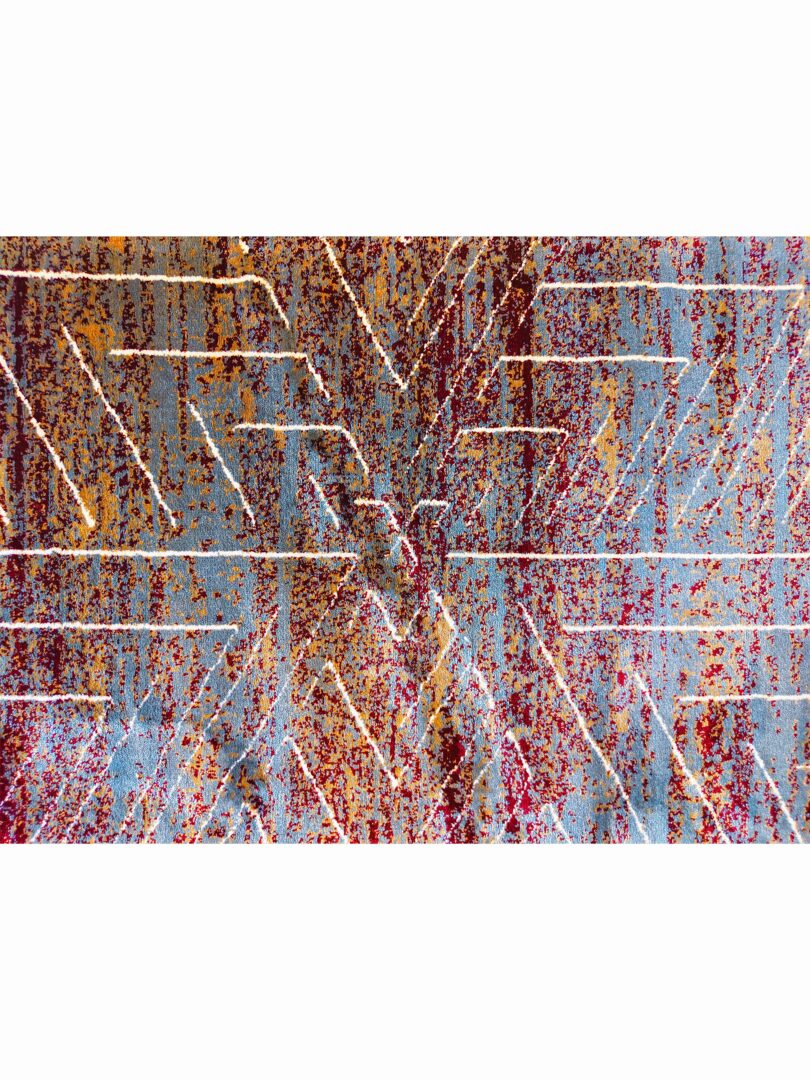 dark abstract rug with intersecting zigzag patterns in blue, brown, and white, placed on a light-colored floor.