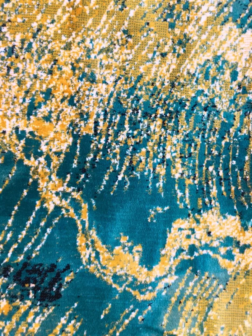 A close-up of the Ocean Ripple Rug with a flowing abstract design in teal, yellow, and white, ideal for dining areas and hallways